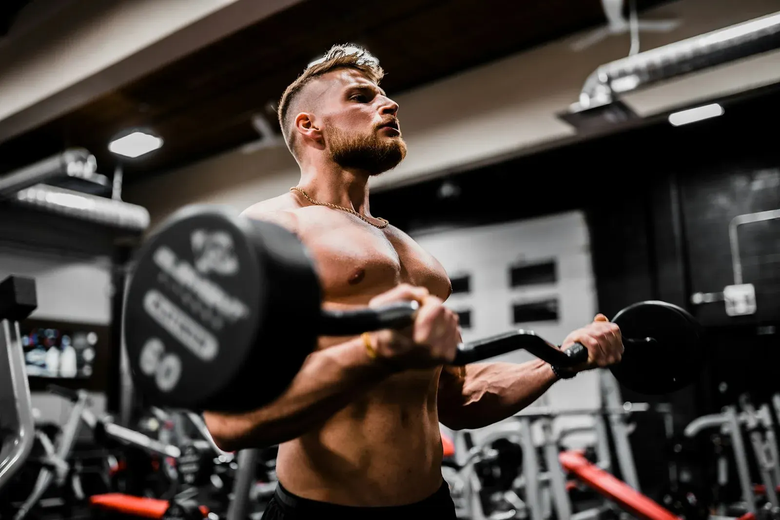Un atleta esegue un curl con bilanciere in sala pesi, ferro vero